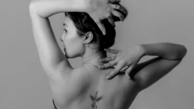 A black and white photo of a woman with tattoos on her back