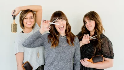 three women holding scissors and brush