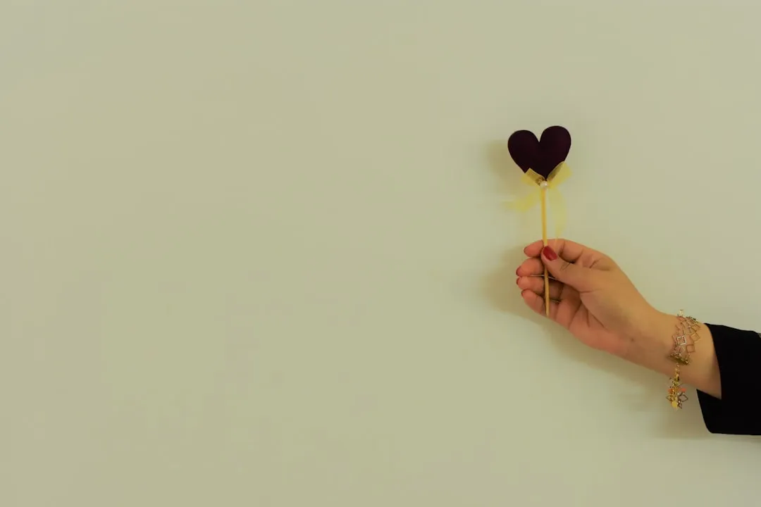 a hand holding a heart shaped piece of paper