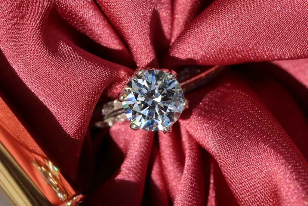 silver diamond ring on red textile