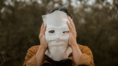 person in brown leather jacket covering face with white face mask