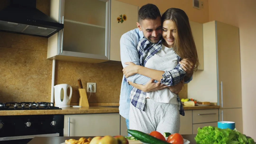 Couple embracing in a bright, modern kitchen.