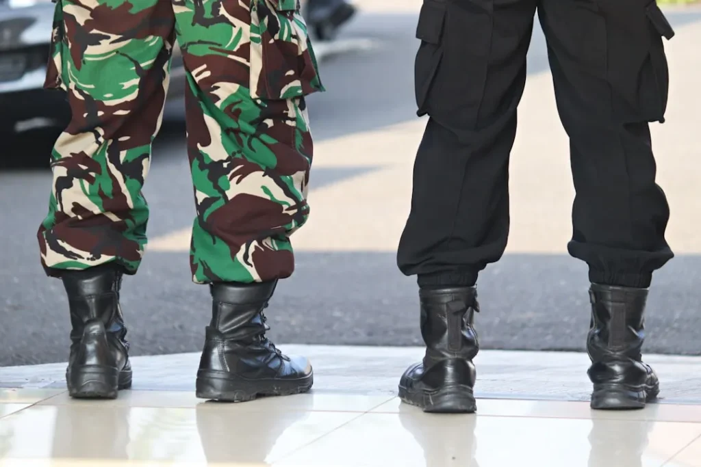 two people in camouflage pants and black boots standing next to each other
