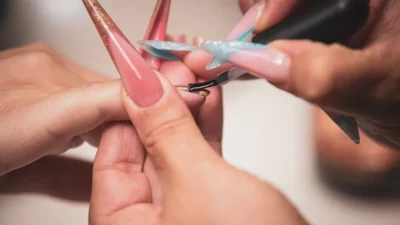 A manicurist paints long artificial nails.