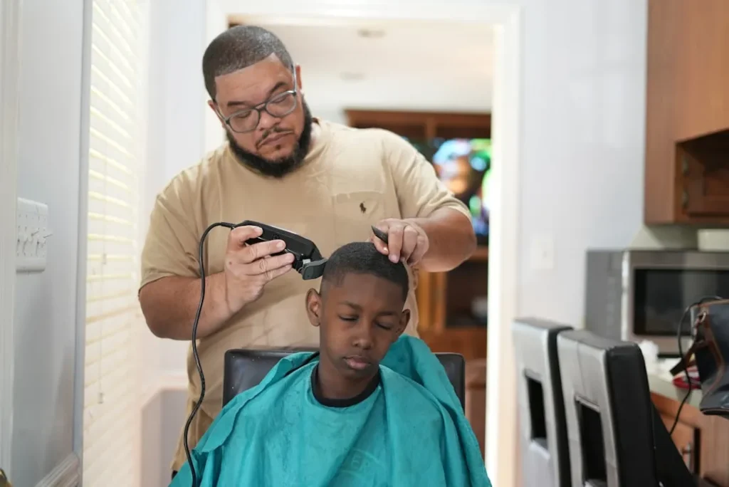 a man cutting a young boy's hair with a hair dryer