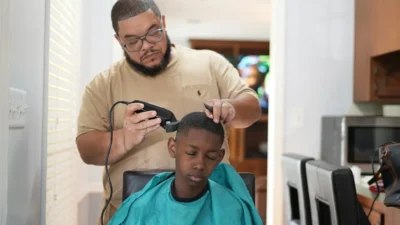 a man cutting a young boy's hair with a hair dryer