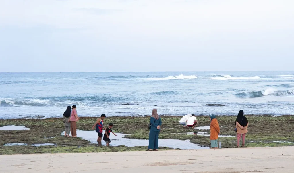 People gather on a rocky shore with the ocean behind.