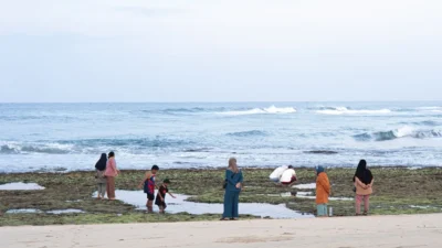 People gather on a rocky shore with the ocean behind.