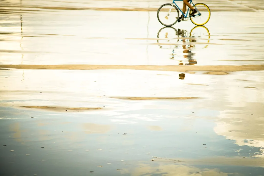 person riding bicycle with reflection to water during daytime