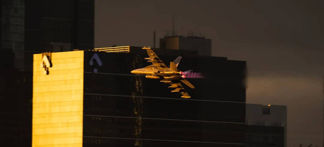 Fighter jet flying past city skyscrapers at dusk.