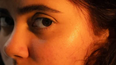 Close-up of a young woman's face with warm lighting.