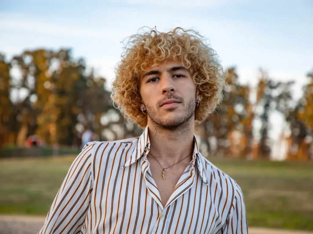 a man with curly hair wearing a striped shirt