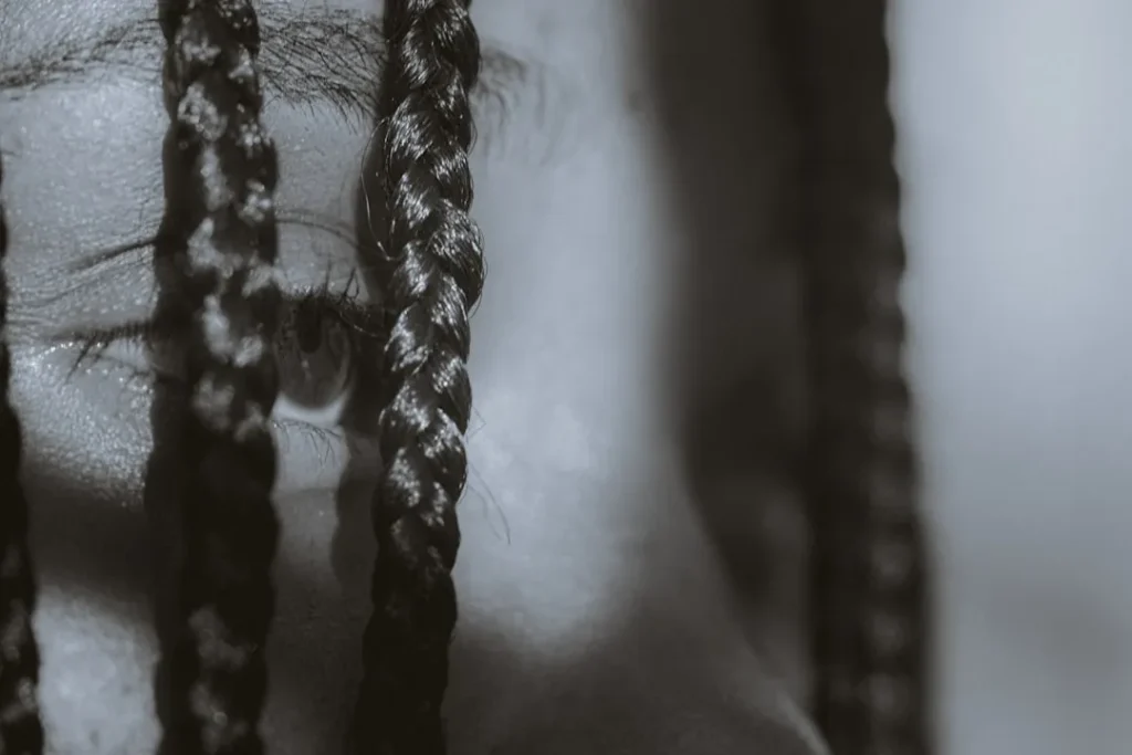 Close-up of a person's eye through braids