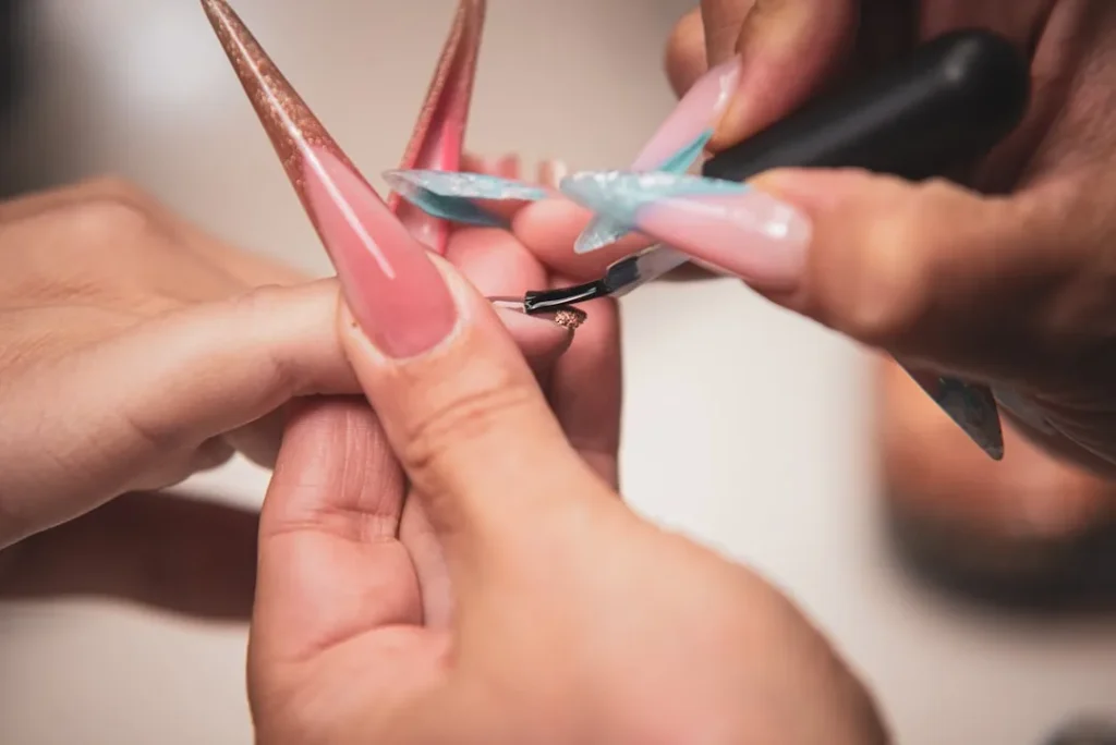 A manicurist paints long artificial nails.