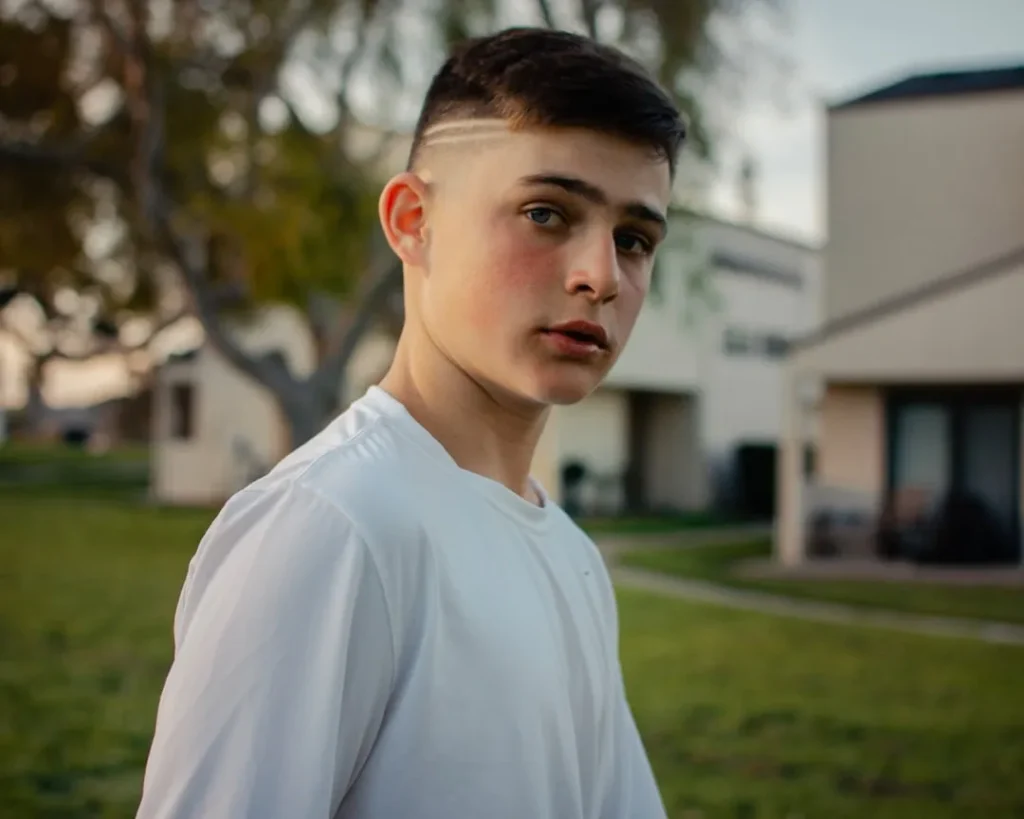 selective focus photography of boy wearing white crew-neck top walking on green grass