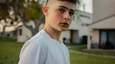selective focus photography of boy wearing white crew-neck top walking on green grass