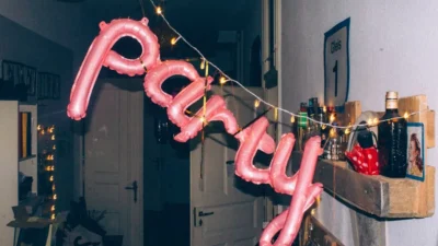 a pink balloon that says party hanging from a string