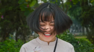 woman smiling closing eyes while flipping her hair