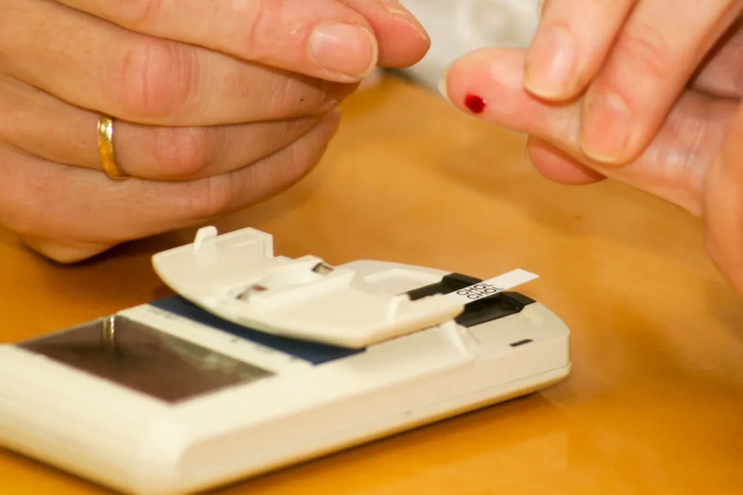person putting blood on glucometer