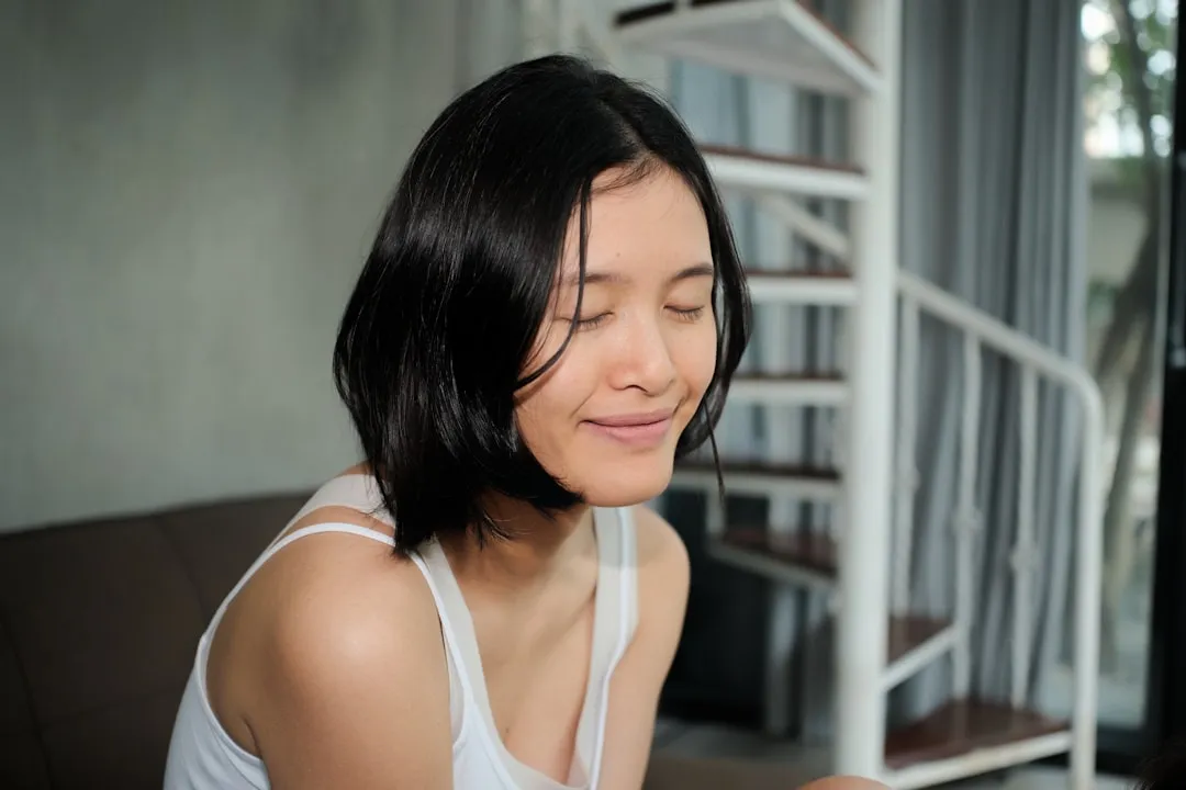 Young woman with short dark hair smiling with eyes closed.