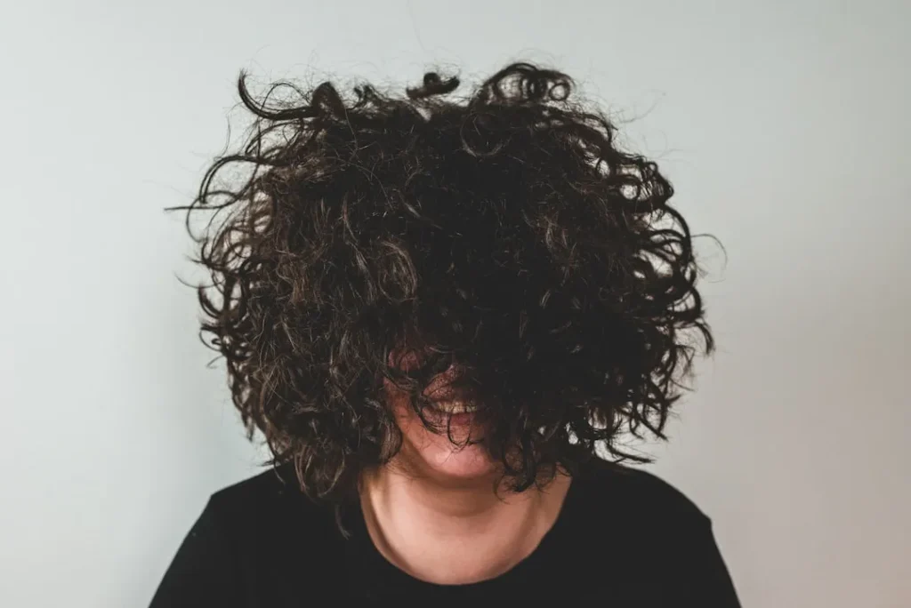 person with curly hair covering face